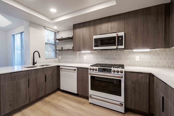 Marble-style quartz countertops, custom cabinetry with backsplash, designed matte black fixtures and cafe series appliances